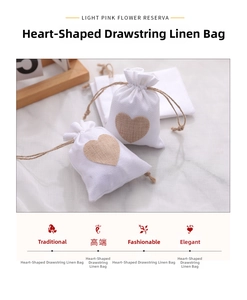 Close-up of white linen drawstring pouches with beige heart prints on marble surface
