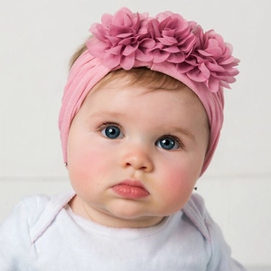 Close-up of baby girl wearing pink chiffon flower nylon headband and white romper