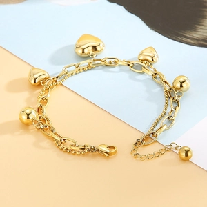 Detailed view of double-layer gold heart charm bracelet on blue and orange paper background