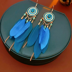 Detail view of bohemian feather earrings with blue enamel and gold metal chains