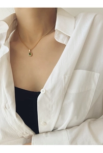 Detail of vintage emerald pendant necklace on female model wearing white shirt
