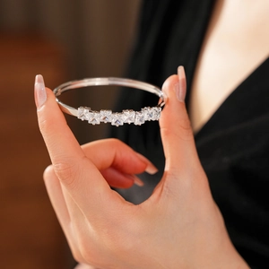 Gros plan d'un bracelet en argent avec sept zircons carrés portés sur la main d'une femme