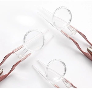 Detail view of professional rose gold contact lens tweezers with integrated magnifying glass