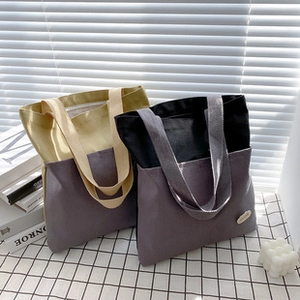 Detailed view of large canvas tote bags in yellow, purple, and black color contrast