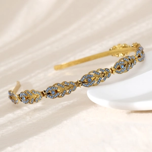 Close-up of golden leaf headband with blue rhinestones on a white ceramic plate