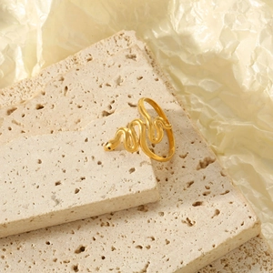Macro shot of gold snake ring with black enamel head on beige stone display block