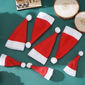 Close-up of mini red and white plush Christmas hats on dark green background