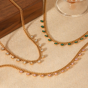 Detail of three gold tassel necklaces with white, green and pink cubic zirconia stones