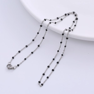 Close-up of silver-tone link necklace with black bead accents on a white edge