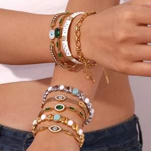 Detail of 18K gold-plated stainless steel bracelets with evil eye and green gemstone charms
