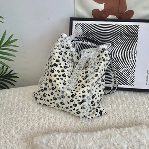 Detailed texture of floral canvas shoulder bag with delicate white lace trim