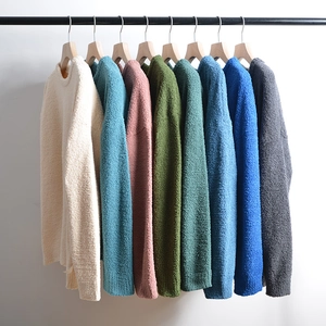 Close-up of knit sweaters in multiple colors hanging on wooden racks with soft chenille texture