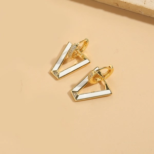 Macro shot of geometric triangle earrings in gold metal with white enamel and zircons