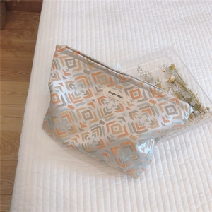 Detail of woven geometric makeup bag featuring a 'simple wish' label and zipper closure