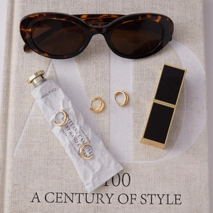 Three pairs of premium 18k gold-plated stainless steel hoop earrings on a magazine background