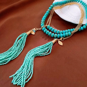 Detail of layered turquoise beaded necklace with gold leaf tassels and fringe design