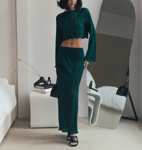Detail of dark green pleated fabric texture on a long sleeve crop top and maxi skirt set