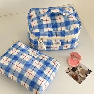 Detail of blue plaid quilted cosmetic bag set showing textured stitching and ribbon pull
