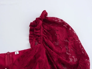 Détail d'une robe en dentelle rouge avec manches bouffantes et étiquette S sur le zip