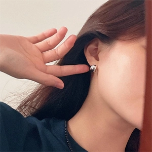 Primo piano di orecchini a perno curvi in argento 925 minimalisti su una modella