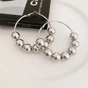Créoles chic en argent avec perles coulissantes en métal sur fond éditorial élégant