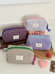 Quilted checkerboard cosmetic bags in multiple colors with woven labels and zippers