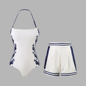 Detailed flat lay of white halter swimsuit and shorts with navy blue wave patterns