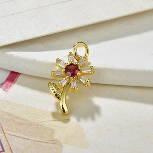 Macro shot of a gold sunflower pendant with red and clear zircon stones on vintage paper