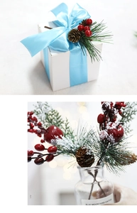Close-up of artificial cedar branches with red berries, pine cones and faux snow texture