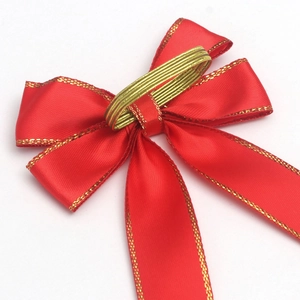 Detail of red velvet Christmas bow with gold edge stitching and elastic gold cord loop