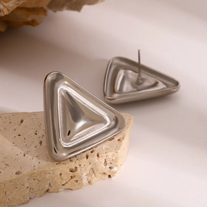 Vue macro de boucles d'oreilles triangulaires en acier argenté sur une pierre naturelle