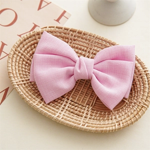 Detailed view of a textured pink fabric bow hair clip placed inside a woven basket