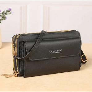 Detail of black pebbled leather crossbody bag with dual golden zippers and front flap