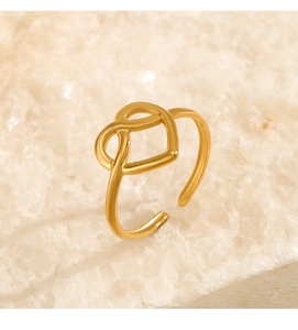 Dettaglio macro dell'anello a nodo di cuore in acciaio dorato su pietra bianca