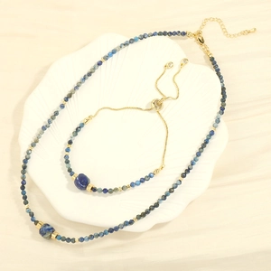 Detailed view of blue stone bead necklace and bracelet set on a white shell tray