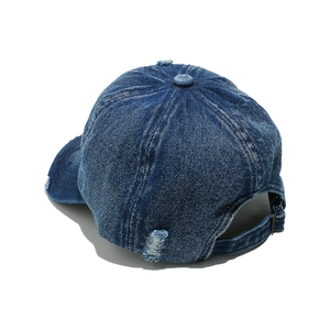 Detail view of washed denim baseball cap with distressed holes and adjustable back strap