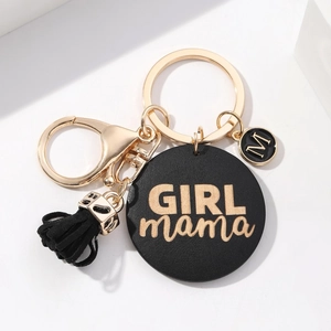 Close-up of black GIRL mama round pendant with golden text and black tassel on keychain