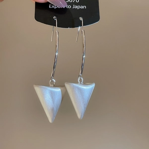Close-up of 18k brushed triangle drop earrings with white pearlescent finish