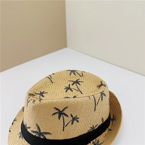 Detail view of woven straw fedora with black palm tree patterns and decorative ribbon