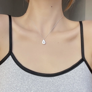 Close-up of S925 silver avocado pendant with white shell inlay worn on neck