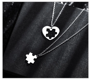 Makroaufnahme von Herz-Puzzle-Halsketten für Paare auf schwarzer Schmuckschachtel mit Bokeh