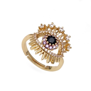 Adjustable gold evil eye ring with purple and white zircon crystals on a white background