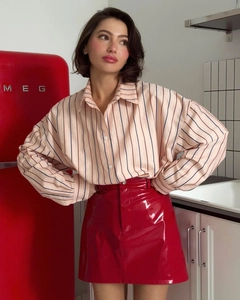 Detail of red shiny faux leather skirt and striped button-down shirt fabric texture