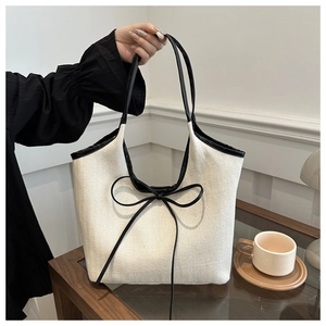 Détail d'un cabas minimaliste avec tissage à chevrons et décoration de nœud noir