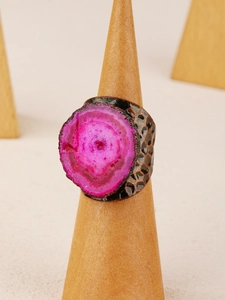 Macro shot of rose red agate ring on wood stand with antique bronze honeycomb texture