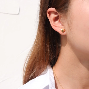 Elegant gold heart stud earrings shown on model with minimalist polished finish