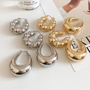 Close-up of elegant gold and silver U-shaped hoop earrings with polished and textured finish