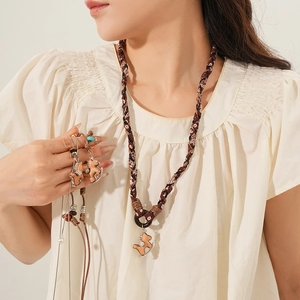 Dettaglio di una collana in corda marrone con ciondolo a forma di cavalluccio in legno