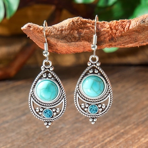 Detail of bohemian drop earrings with turquoise beads hanging on a rustic wooden branch