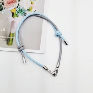 Detail of adjustable two-tone leather phone lanyard with metal clasps and knot design